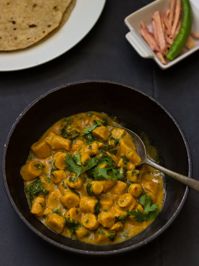 A spoonful of Gatte Ki Sabji being taken from the bowl, showcasing the texture of the gattas