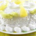 Best eggless pineapple gateau on a white plate, topped with fresh pineapple slices and whipped cream