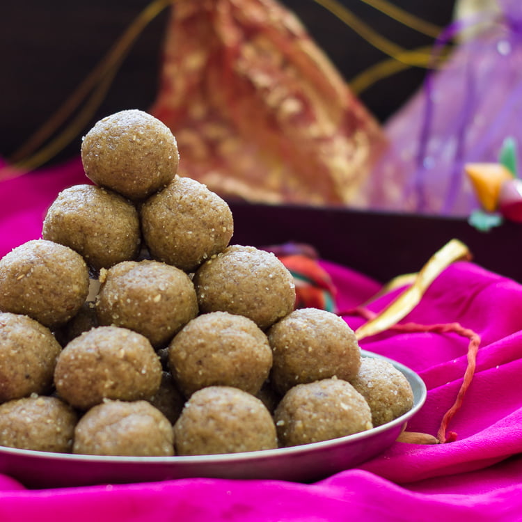 Golden sesame seed laddus arranged in a decorative bowl