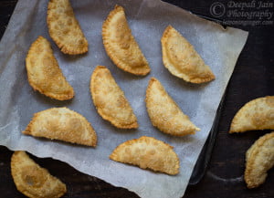 A close-up of golden-brown Gujiya filled with sweet khoya, arranged beautifully on a plate