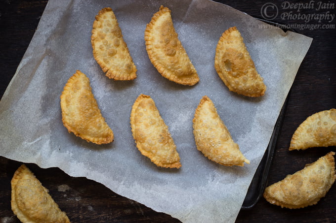 A close-up of golden-brown Gujiya filled with sweet khoya, arranged beautifully on a plate