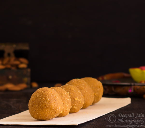 Placing freshly rolled besan ladoos on a serving tray.