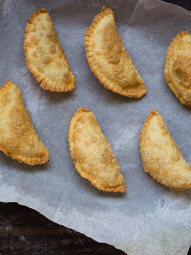 Freshly fried Karanji with crispy edges and a glossy finish, placed on a festive tray