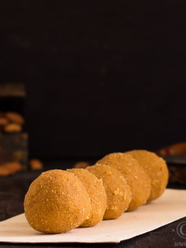 Placing freshly rolled besan ladoos on a serving tray.