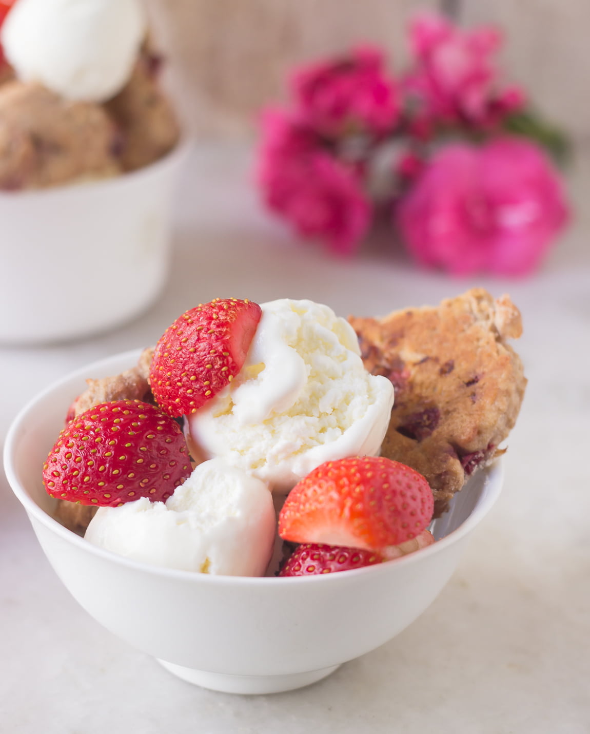 A bowl full of freshly baked strawberry shortcake scones with a side of clotted cream
