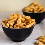 A bowl full of crispy, golden-brown Namak Para stacked neatly.