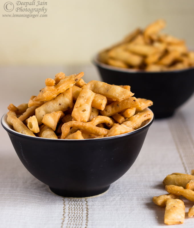 A bowl full of crispy, golden-brown Namak Para stacked neatly.
