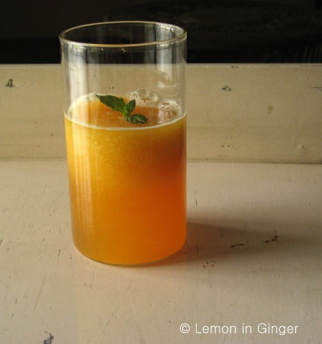 A clear glass filled with Bel Ka Sharbat, showcasing its rich, amber color