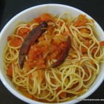 Ingredients for Spaghetti Arrabiata laid out: pasta, tomatoes, garlic, and chili flakes