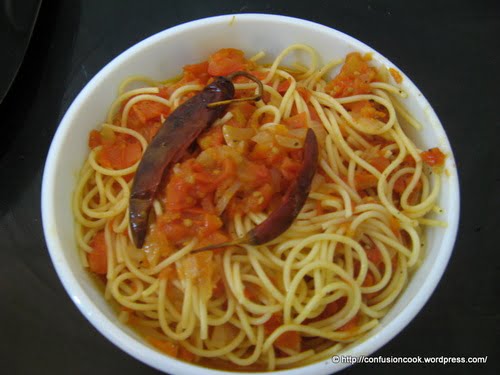 Ingredients for Spaghetti Arrabiata laid out: pasta, tomatoes, garlic, and chili flakes