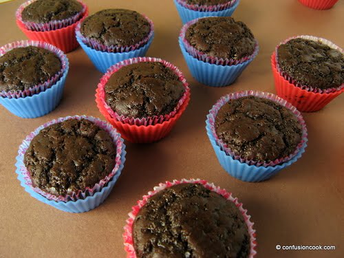 A batch of rich chocolate cupcakes with glossy frosting and rainbow sprinkles