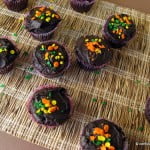 Freshly baked chocolate cupcakes with vibrant sprinkles on a cooling rack