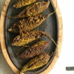 Golden brown stuffed karela cooking on a wooden plate