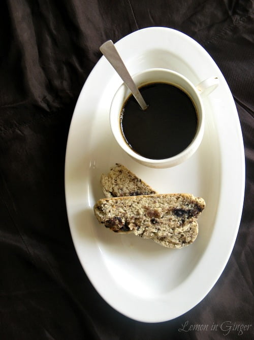 Pile of chocolate biscotti with small ginger chunks on a white plate