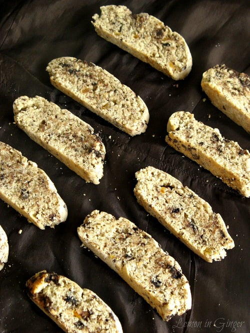 A row of freshly baked chocolate biscotti with visible chunks of candied ginger