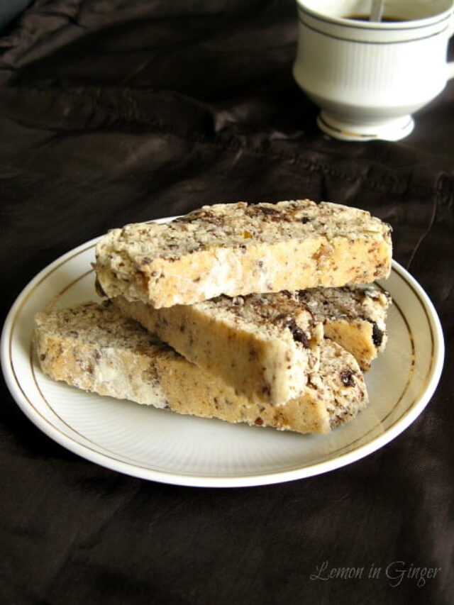 Pile of chocolate biscotti with small ginger chunks on a white plate