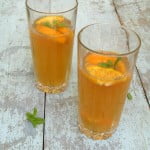 Glass of orange iced tea with ice cubes and orange slices