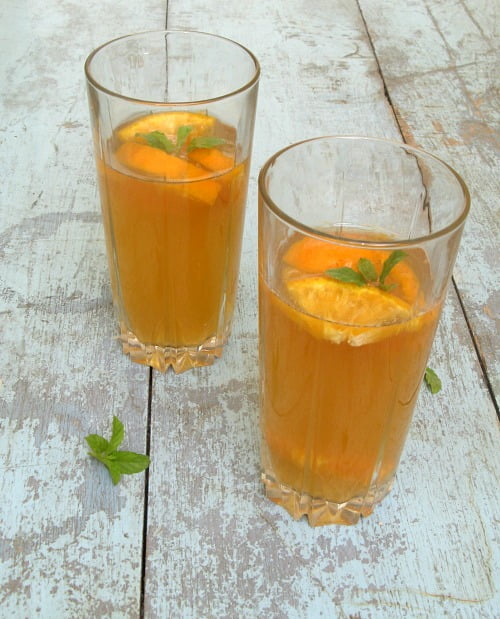 Glass of orange iced tea with ice cubes and orange slices