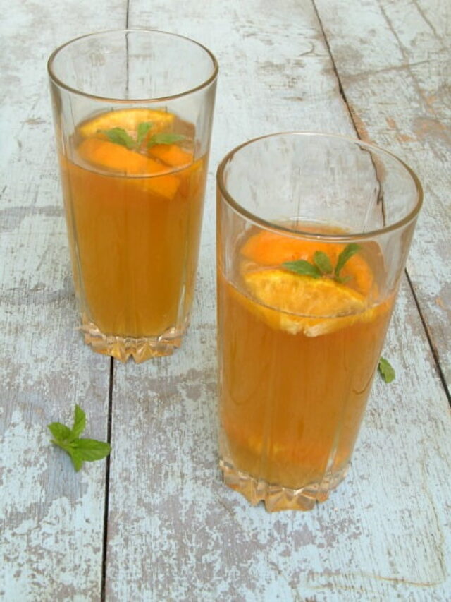 Glass of orange iced tea with ice cubes and orange slices