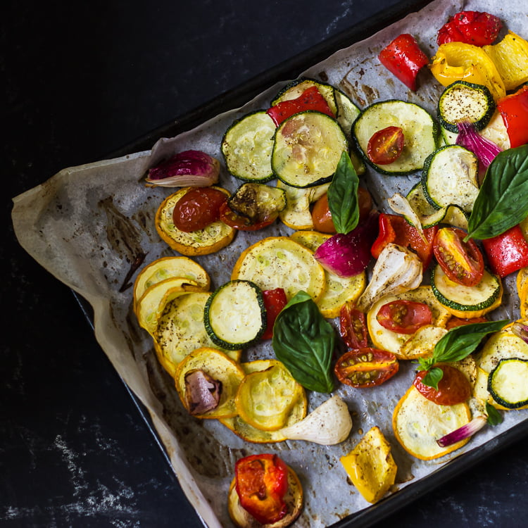 Oven-roasted vegetables served in a bowl with a side of lemon wedges