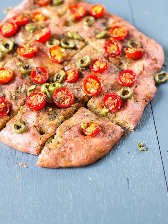 Overhead shot of beetroot focaccia decorated with rosemary and garlic