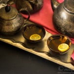 Two glasses filled with hot lemon tea with a teapot