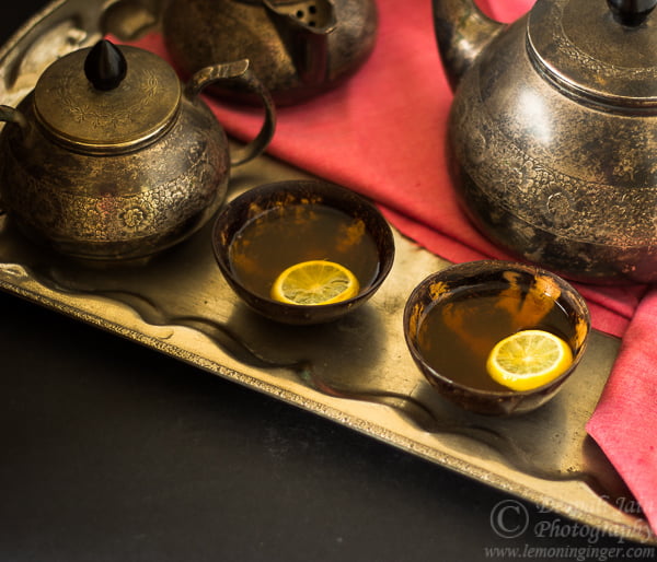 A steaming cup of hot lemon tea with a slice of lemon on the rim, ready to enjoy