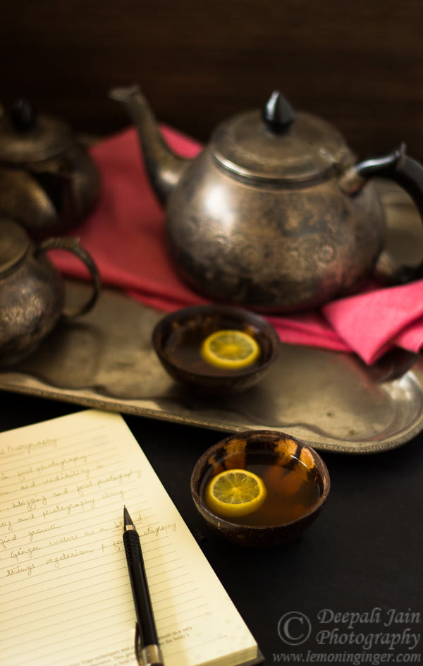 A setup with a cup of hot lemon tea, a teapot, and a diary