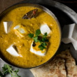 Kadai Paneer plated beautifully with roti and sliced onions on a wooden table