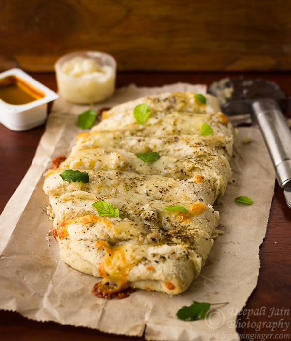 Close-up of golden brown Dominos style cheesy breadsticks with melted cheese