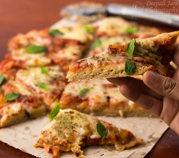 A hand picking up the slice of the pizza to eat