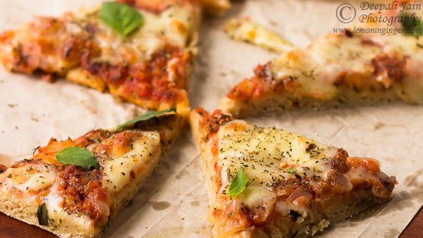 Sliced whole wheat Margherita pizza topped with basil and served on a white plate