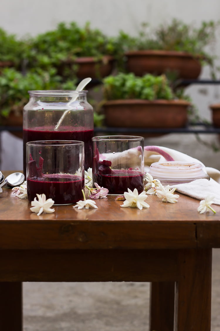 Overhead shot of freshly prepared Beetroot Carrot Kanji in a glass, garnished with mustard seeds