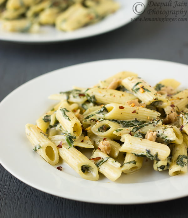 Pasta with creamy spinach sauce being plated on a serving dish