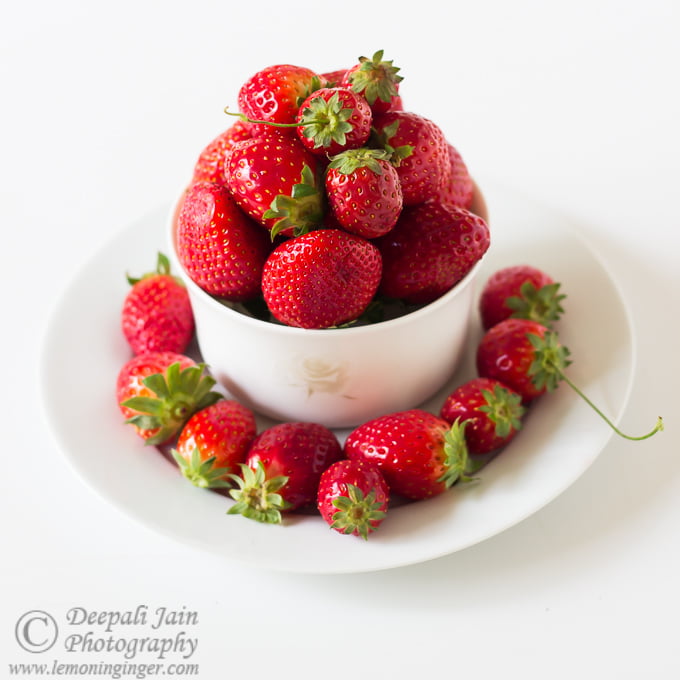 Fresh strawberries displayed in a white bowl and plate