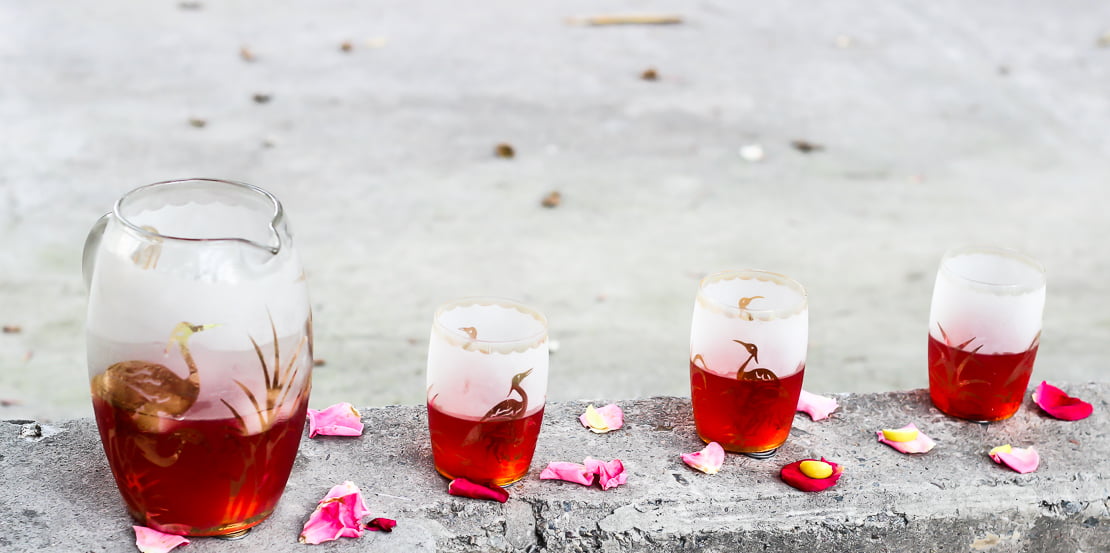 A pitcher of Rooh Afza Sharbat surrounded by fresh mint and lemon slices