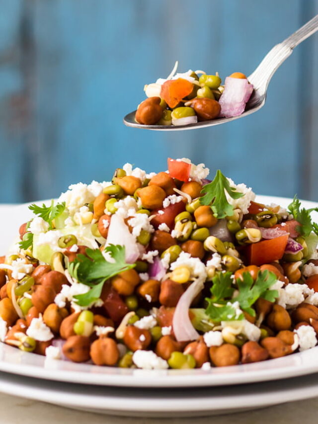 A spoonful of sprouted moong salad showing a mix of fresh vegetables and sprouts.