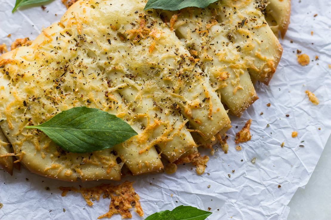 Close-up of melted cheese and herbs on freshly baked breadsticks