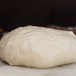 Ball of freshly kneaded homemade pizza dough on a floured surface