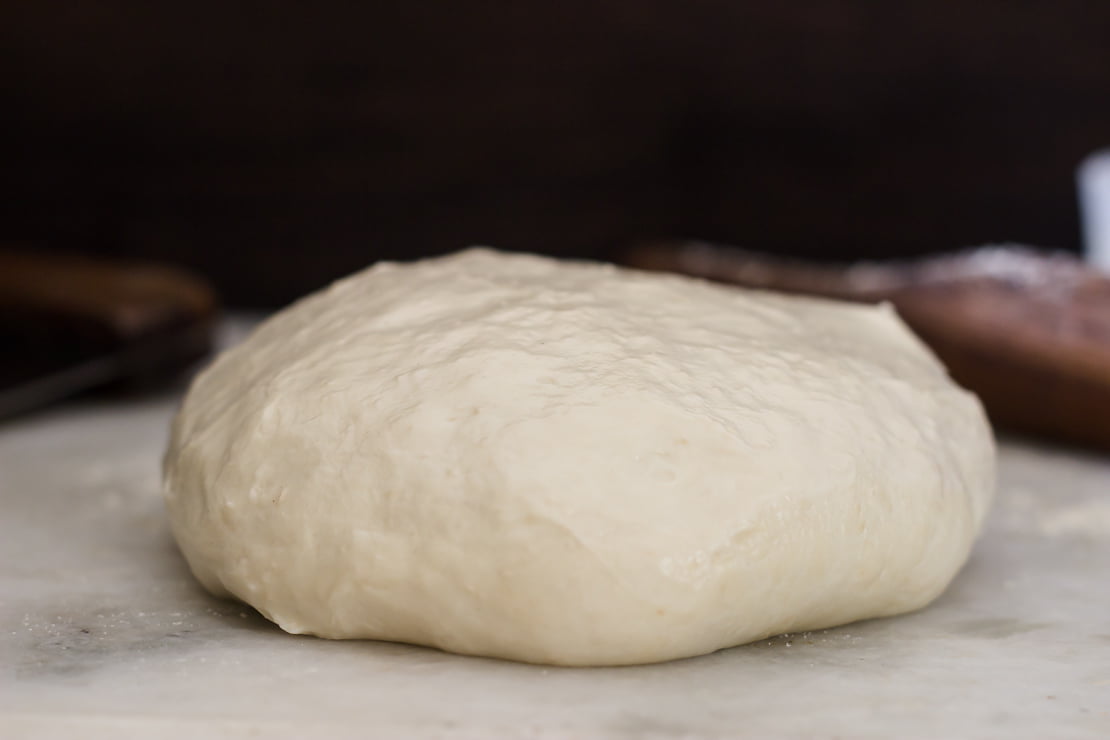 Ball of freshly kneaded homemade pizza dough on a floured surface