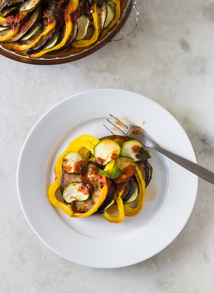 A slice of Baked Ratatouille being lifted from the dish, revealing the layers