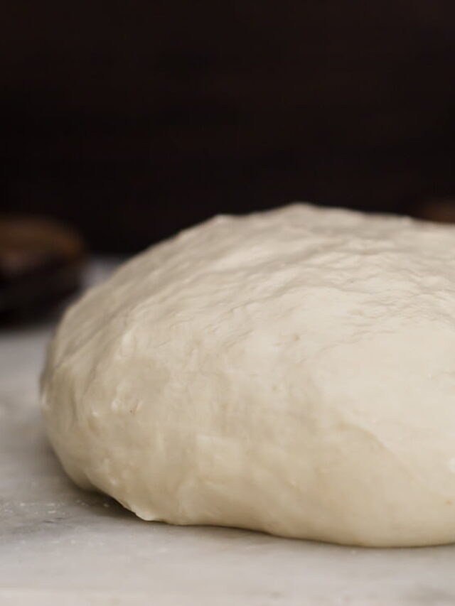 Ball of freshly kneaded homemade pizza dough on a floured surface