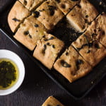 Slicing into freshly baked whole wheat basil focaccia bread