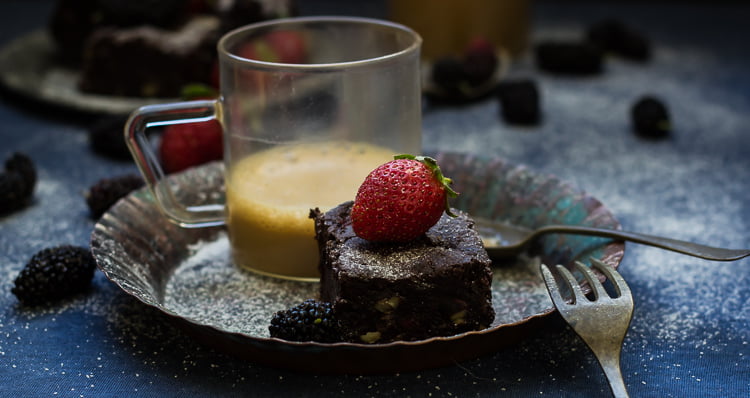 A single brownie on a white plate with a drizzle of chocolate sauce