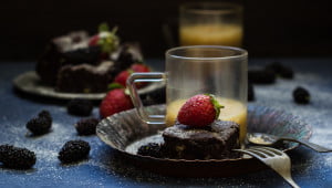 A dessert plate with brownies, whipped cream, and fresh strawberry garnish