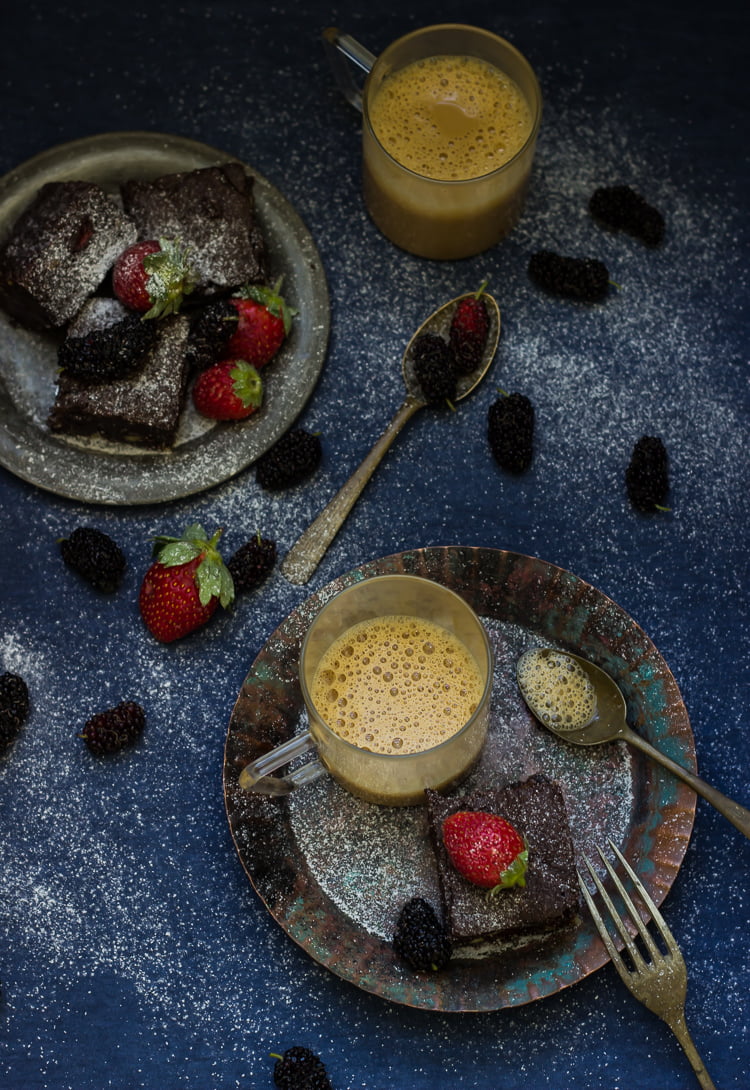 A stack of rich, gooey brownies with roasted strawberries peeking through
