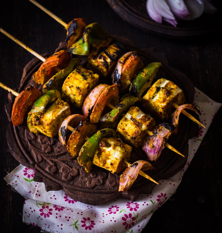 Close-up of Tandoori Paneer Tikka skewers grilled to perfection with charred edges