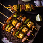 Close-up of Tandoori Paneer Tikka skewers grilled to perfection with charred edges