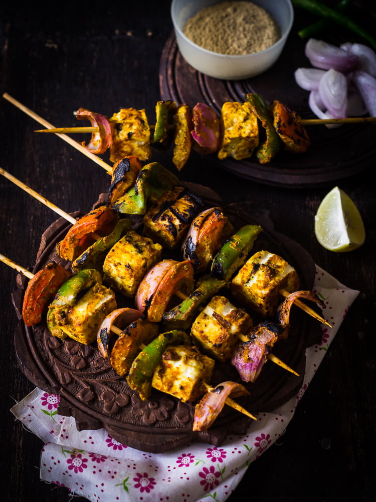 Vibrant paneer tikka served with onion rings, lemon wedges, and green chutney