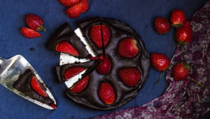 Close-up of a slice of no-bake chocolate strawberry tart with fresh strawberries on top